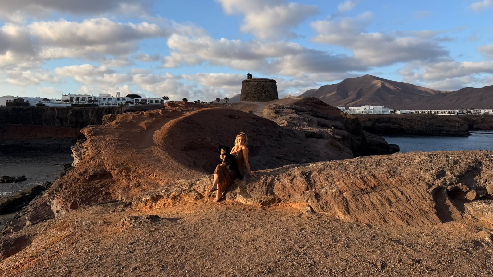 Sentada en la roca con el Castillo de las Coloradas al atardecer