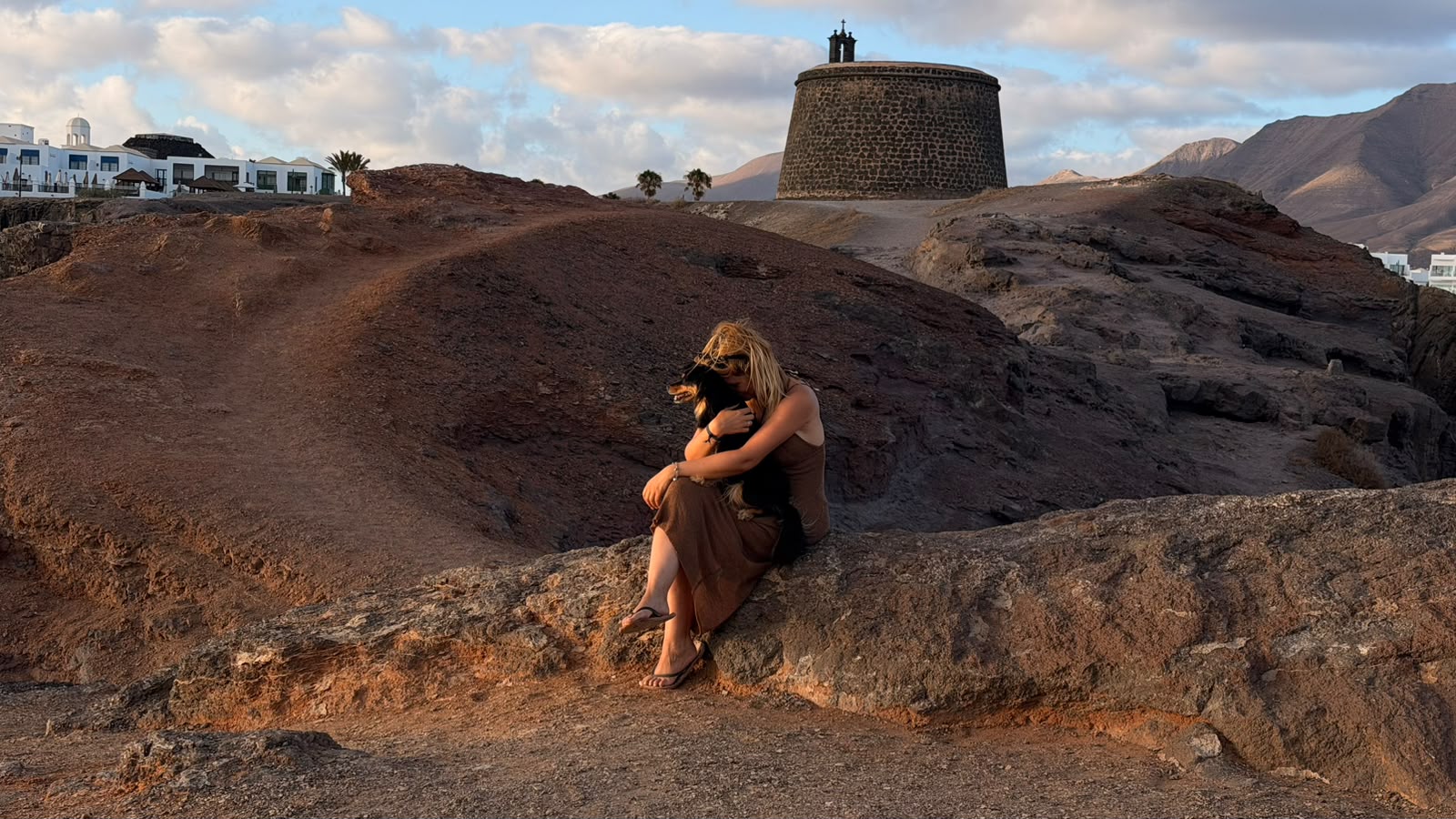 Abrazando al perrito en la roca con el Castillo de las Coloradas detrás