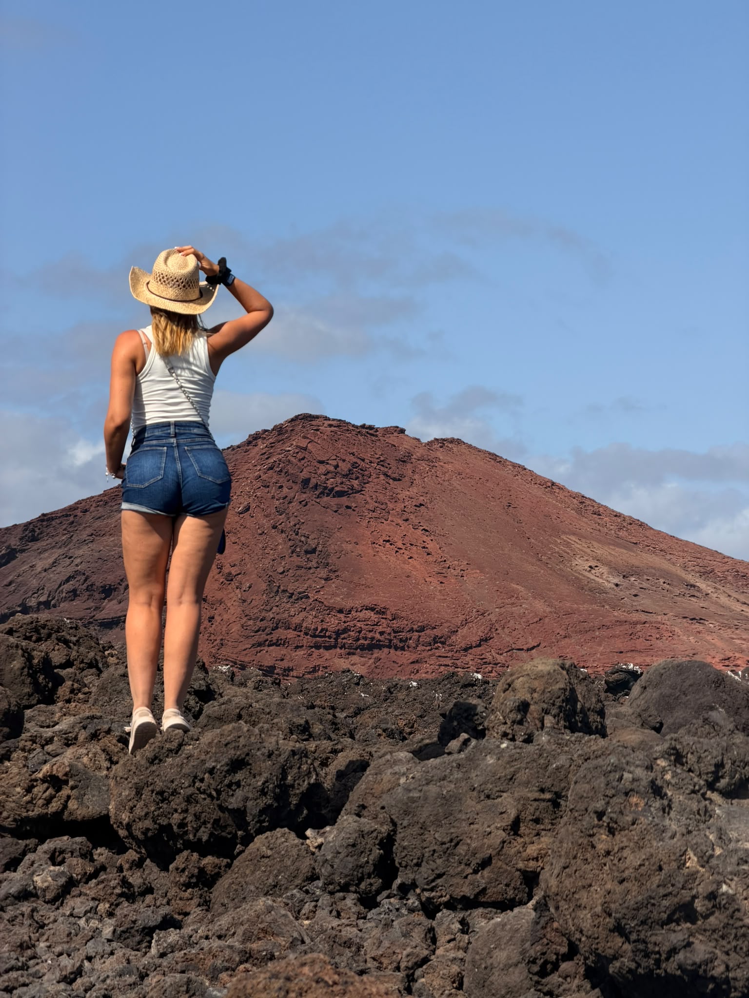 Sobre la lava mirando un cono volcánico rojo